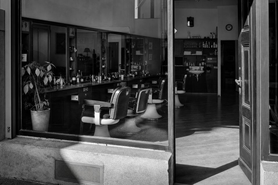Schwarz-weißes Stimmungsbild: Fassade eines traditionellen Friseursalons bei Tageslicht, ruhig und sachlich