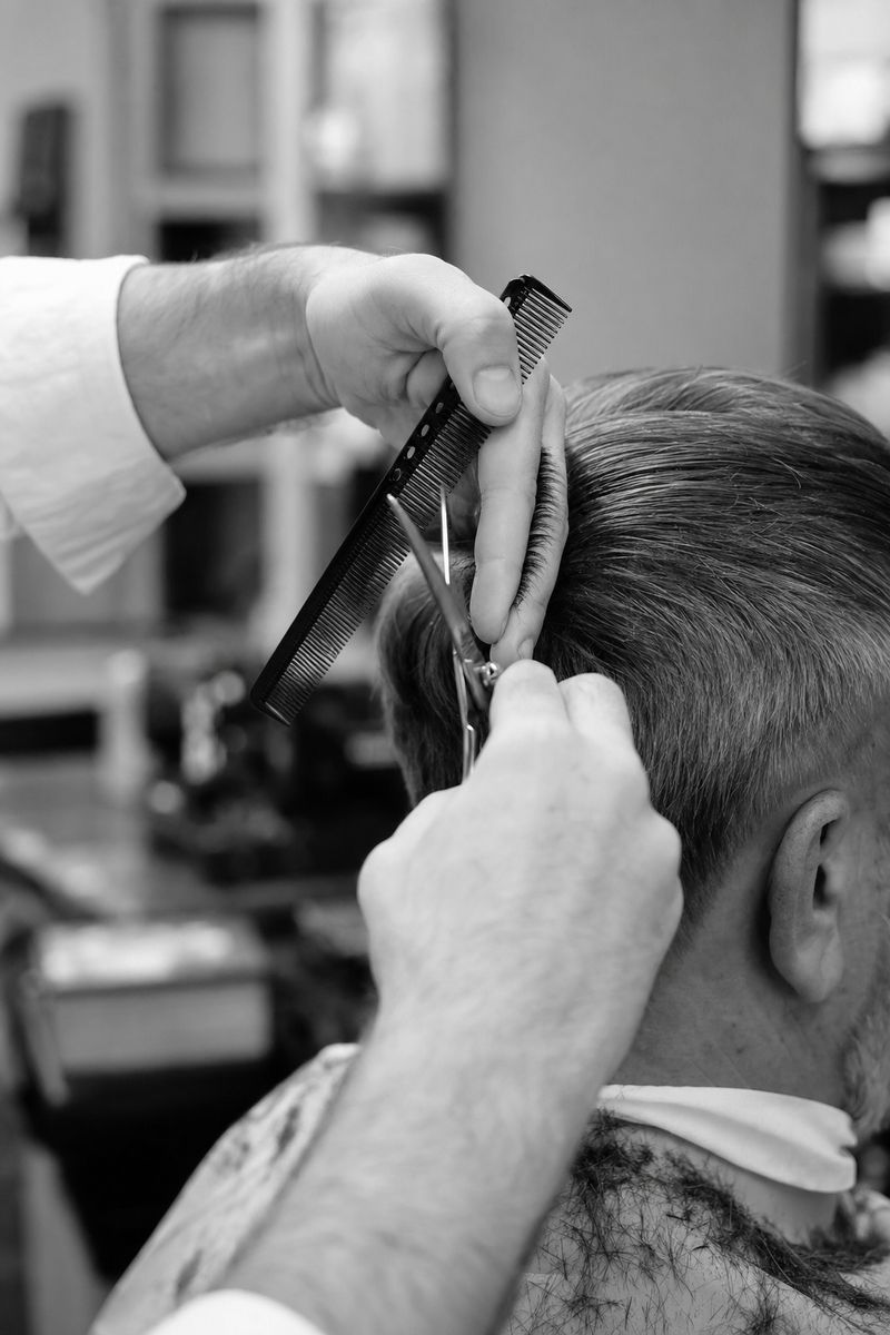 Schwarz-weißes Stimmungsbild: Hände mit Schere und Kamm beim Haarschnitt, kein Gesicht sichtbar